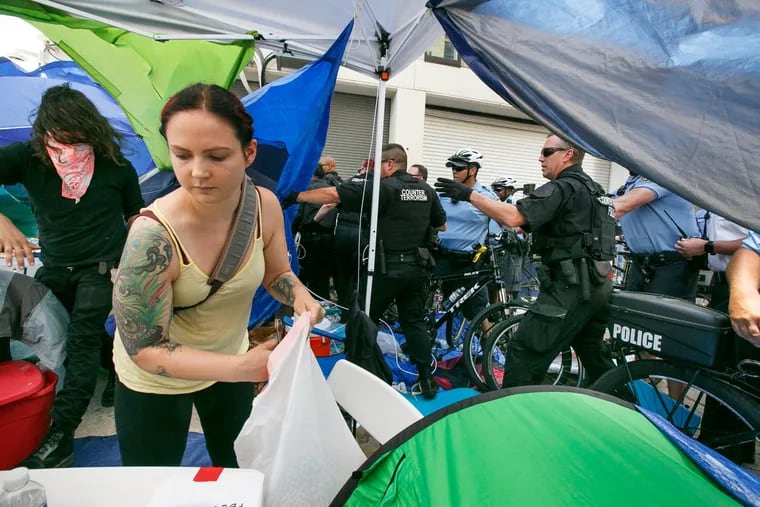 Protestors, left, move parts of their camp, as requested by police, at the same time Police enter and dismantle the protestor camp at 8th and Cherry Streets, outside the ICE office, in Philadelphia, July 5, 2018.