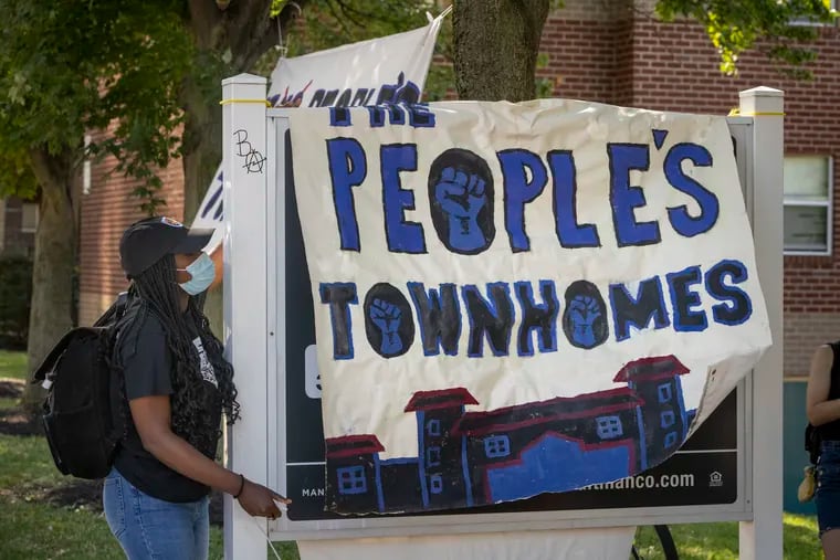 A banner is dropped over sign renaming the University City Townhomes the People’s Townhomes.