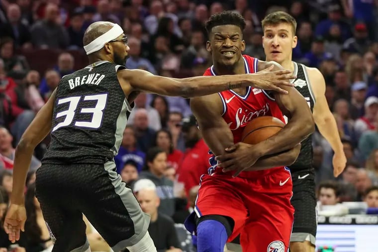 Sixers forward Jimmy Butler protects the ball as he drives to the basket against Sacramento Kings player Corey Brewer in the second quarter of a game against the Sacramento Kings at the Wells Fargo Center in Philadelphia on Friday, March 15, 2019.