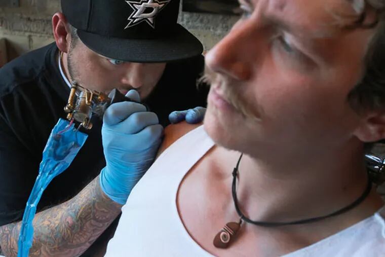 Tattoo artist Cody Biggs works on a tattoo on the arm of Adam Metzger in Dallas on May 15, 2014. Experts advise making sure you are up to date on your immunizations, especially hepatitis and tetanus, before getting a tattoo. (Louis DeLuca/Dallas Morning News/MCT)