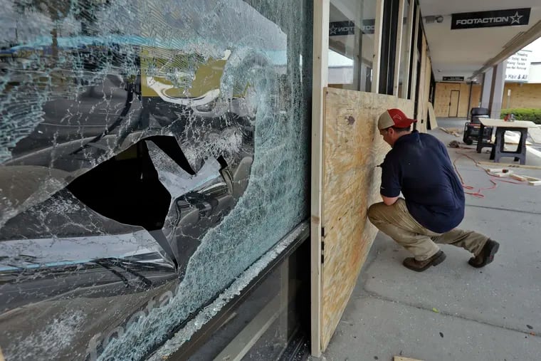 Jon McCloud, general manager of Vet Cor, boards up the windows of a shoe store Monday in Tampa, Fla., after the store was looted by protesters during a demonstration Saturday night.
