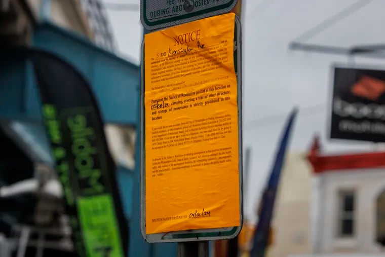 A sign informing people along Kensington Avenue that on Wednesday, May 8, the city will be removing tents and other structures from the avenue.