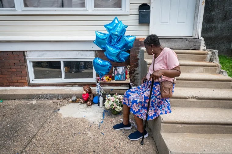 Sharon Johnson, first cousin of Joseph Wamah Jr., 31, sits on the front steps of Wamah's house next to a memorial displaying his photograph on Monday, July 10, 2023.