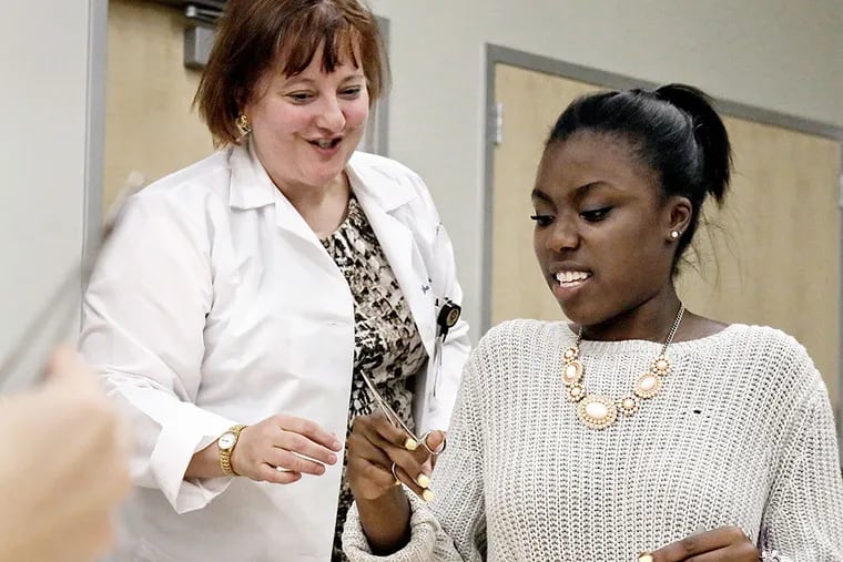 Martha Matthews shows Haddonfield Memorial High School student Naja Lopez how to hold forceps. For many students, the MEDacademy program shows what it takes to make it in the field. ELIZABETH ROBERTSON / Staff Photographer