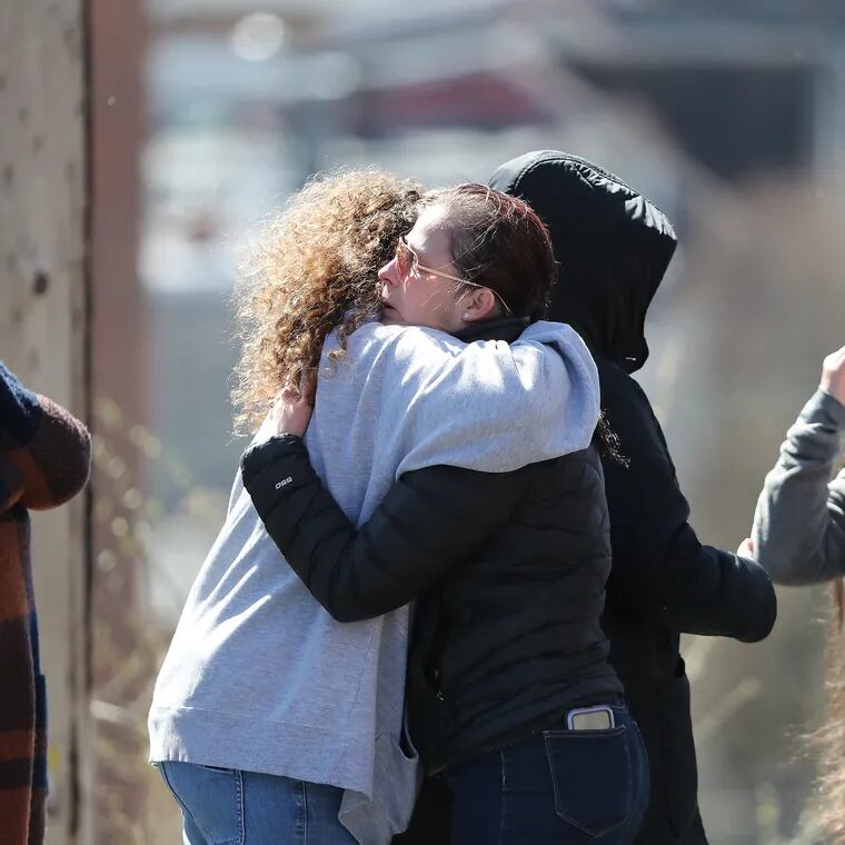 A group, who identified themselves as factory workers, embrace after a body was removed from the scene of the explosion at the R.M. Palmer chocolate factory in West Reading, Pa. on March 26, 2023.