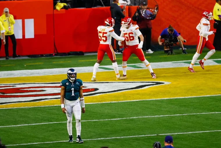 Eagles quarterback Jalen Hurts walks back to the sideline as the Kansas City Chiefs celebrate the touchdown they scored on a 36-yard return of Hurts' fumble.