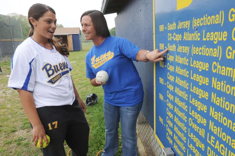 Dawn Scott and her daughter Brittany hold the game balls from their perfect games against Sacred Heart while comparing their teams' records at Buena's field. Scott, then Dawn Lacer,is seen at right during her big game in 1981.