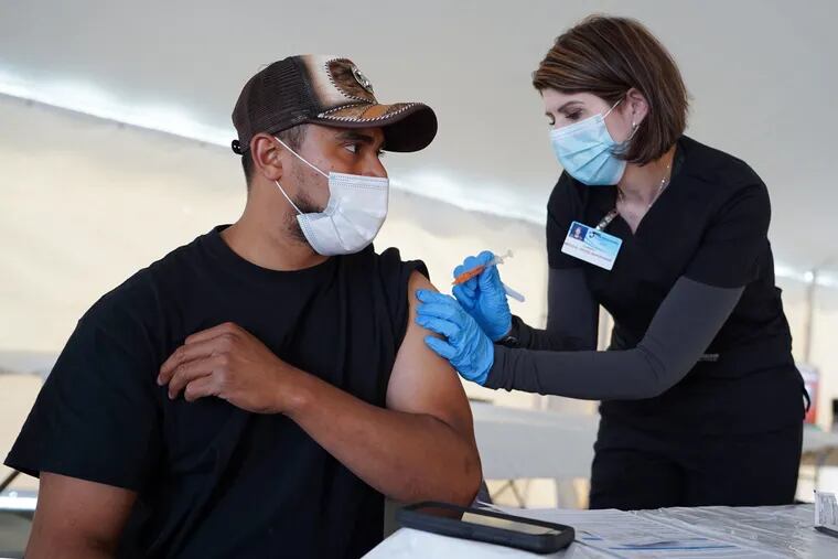 Giorgi Mushroom Company worker Juan Frutos gets a vaccine shot from Penn State Health nurse Christy Daniels during a clinic facilitated by Latino Connection's mobile unit. The Wolf administration hired the group this spring to address persistent disparities.
