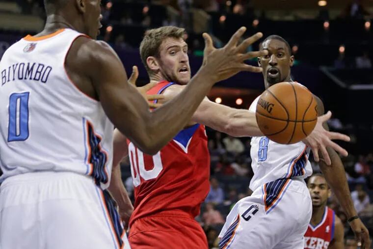 Bobcats' Ben Gordon, right, passes the ball around Philadelphia 76ers' Spencer Hawes, center, to Bismack Biyombo, left, during the first half of an NBA basketball game in Charlotte, N.C., Friday, Dec. 6, 2013. (Chuck Burton/AP)