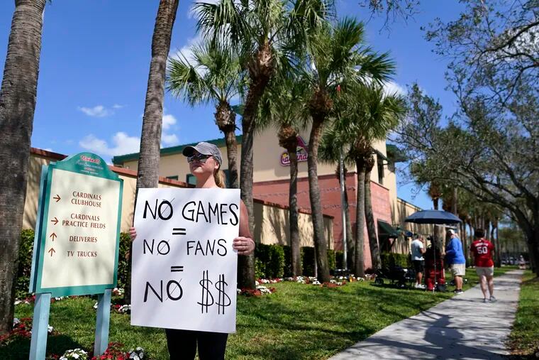 Tigers fan Genna Perugini holds a sign outside of Roger Dean Stadium during negotiations between Major League Baseball and the players union on Monday.