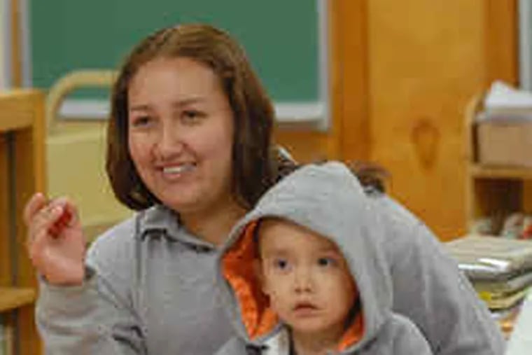 Learning English and gaining confidence, Eva Lopez, with son Adrian in her lap, plays a Halloween word game during a Bristol Township school program for ESL families.
