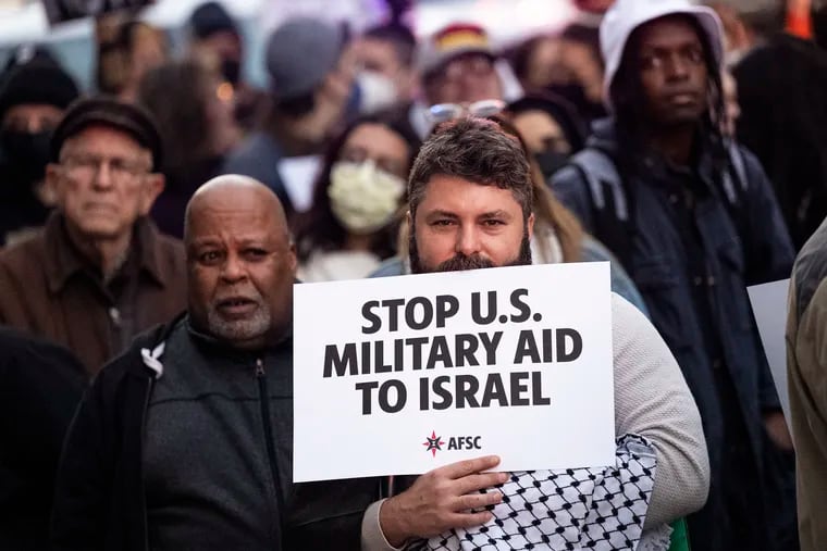 A man holds a sign calling for the U.S. military to stop sending aid to Israel during a rally calling for a ceasefire between Israel and Hamas on Monday, Nov. 13, 2023, outside the office of Sen. John Fetterman, D-Pa, in Philadelphia.