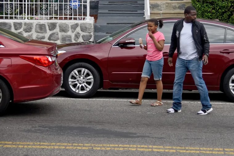 Omar Hanible and his daughter, Laila Hanible, 8, cross 57th Street near Locust Street to head back to his mother Mary Tate’s house after getting ice cream April 30, 2017. Using the latest crash data from the state the area around 57th and Walnut Streets been identified as having a particularly high number of car crashes, including pedestrian and bicycle crashes.