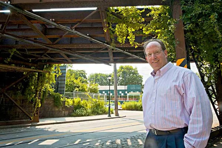 Ken Weinstein stands under an old railroad trestle that is holding up development of the proposed Cresheim Trail which would run near his Trolly Car diner ( in the background) in Mt. Airy. (  RON TARVER / Staff Photographer ) July 23 2014