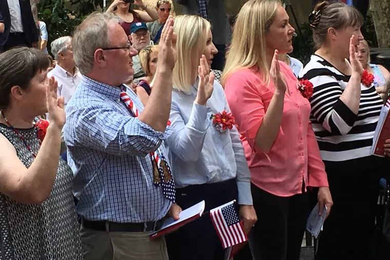 Mariana Molosag (center) flanked by other immigrants takes the oath of citizenship on Flag Day at the Betsy Ross House