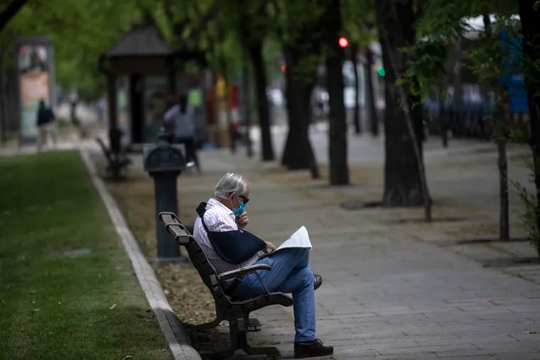 A man wearing a face mask to combat the spread of the coronavirus reads a newspaper in Madrid, Spain.