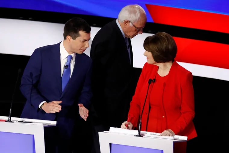 Democratic presidential candidates former South Bend Mayor Pete Buttigieg (left) and Sen. Amy Klobuchar talk while Sen. Bernie Sanders heads off stage during a break in Tuesday's presidential primary debate.