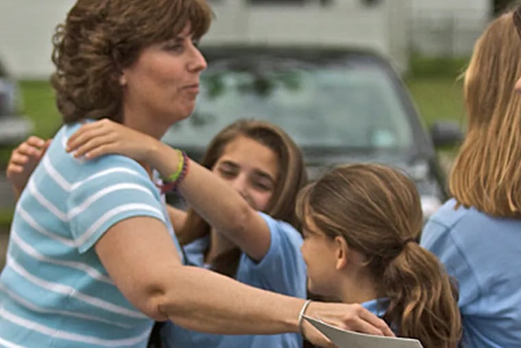 Denise Lundholm, a mother of a student, a former student herself and a 5th-, 6th-, 7th- and 8th-grade math teacher  at Sacred Heart hugs students goodbye. ( John Costello / Staff Photographer )