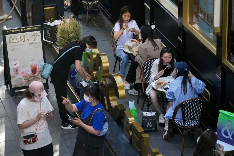 Women wearing face masks (lower left) chat as people eat at a reopened restaurant in a shopping mall in Beijing.