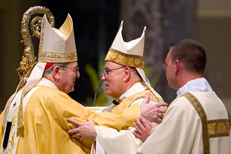 Retiring Cardinal Justin Rigali (left) embraces his successor, Archbishop Charles J. Chaput, at the Cathedral Basilica of SS. Peter and Paul. (Charles Fox / Staff Photographer)