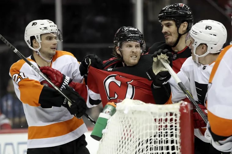 Flyers’ Scott Laughton (left) and defenseman Travis Sanheim argue with Devils’ Blake Coleman (center left) and Brian Boyle during the second period.