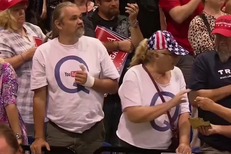 Two attendees at a rally held by President Donald Trump Tuesday night wear shirts promoting one of the more bizarre conspiracy theories to emerge during his presidency.