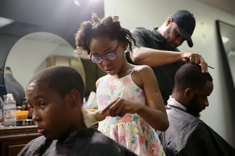 Neijae Graham-Henries, 8, second from left, gives Rymir Ware, 14, far left, a haircut at Supreme Clientele Hair Gallery in Darby.