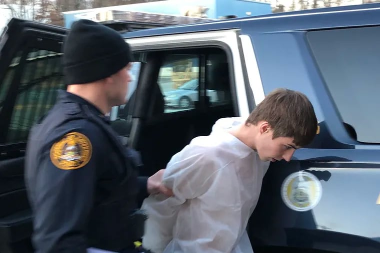 James McCauley, 17, is led into district court in Broomall by a police officer. McCauley is accused of shooting another teen in the face during a botched drug deal.