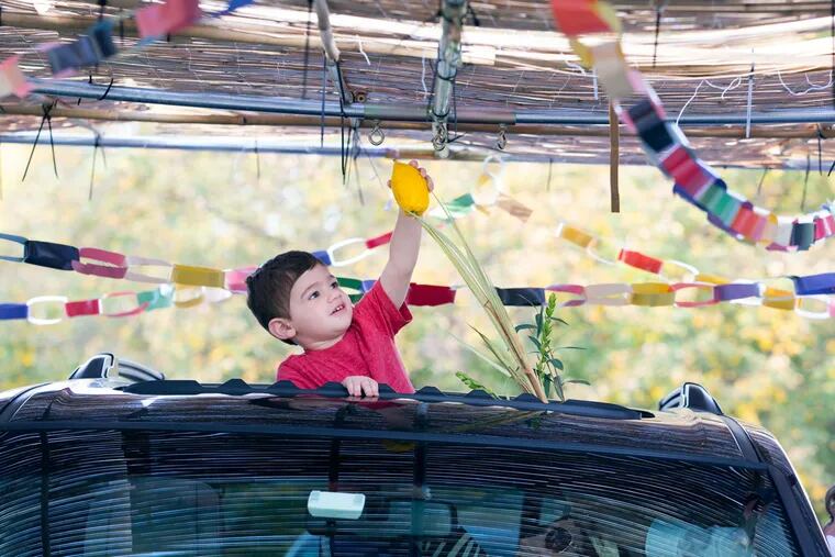 Zachary Wuhl, 2, in Har Zion Temple’s drive-through sukkah, built with green plastic walls and construction-paper decorations made by children.