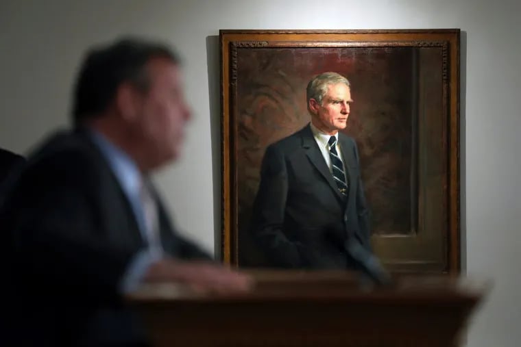 In this July 3, 2017, file photo, former New Jersey Gov. Brendan Byrne's portrait hangs nearby as New Jersey Gov. Chris Christie speaks in Trenton, N.J. The official portrait of Christie, a two-term Republican governor, by Australian artist Paul Newton will cost $85,000, The Record reported Thursday, April 19, 2018, more than taxpayers shelled out for paintings of his three Democratic predecessors combined.