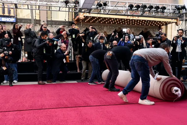 A crowd of photographers take photos of crew workers as they roll out the red carpet for Sunday's 92nd Academy Awards at the Dolby Theatre on Feb. 5, 2020, in Los Angeles. Experts say the company you choose to buy from and install a carpet is a critical decision. (AP Photo/Chris Pizzello)