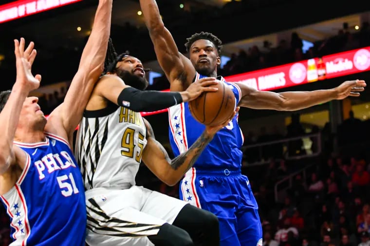 Atlanta Hawks forward DeAndre' Bembry, center, splits the defense of Philadelphia 76ers center Boban Marjanovic (51) and guard Jimmy Butler, right, as he goes to the basket during the first half of an NBA basketball game Saturday, March 23, 2019, in Atlanta. (AP Photo/John Amis)