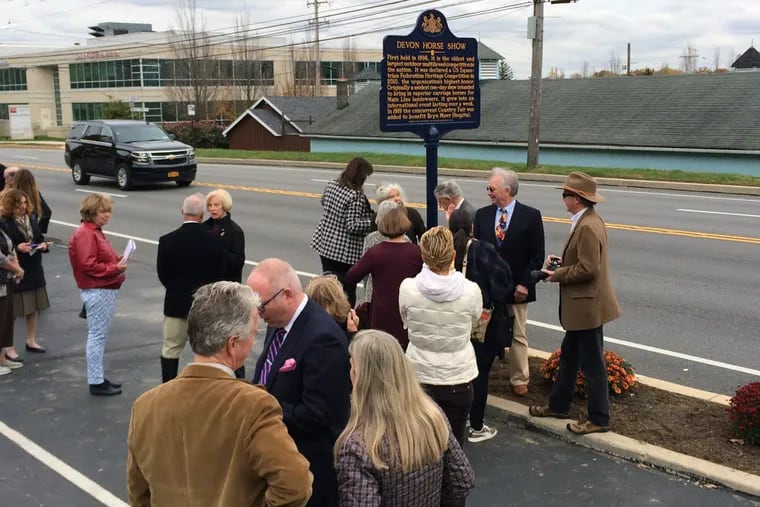 The Devon Horse Show historical marker is unveiled by David Reinfeld, interim president of the Chester County Historical Society; Francis Jacobs, Chester County Historical Society and former Devon Horse Show board member; Michael Morrison, president of Tredyffrin-Easttown Historical Society; and Devon Preservation Alliance president Josh Macel. Eugene Hough of Heritage Guild Works looks on.