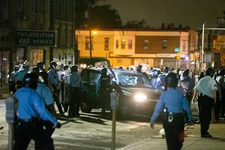 Officers surround a vehicle on Chestnut Street between 52nd and 53rd Streets in West Philadelphia early Tuesday morning during unrest sparked by the fatal police shooting Monday afternoon of Walter Wallace Jr.