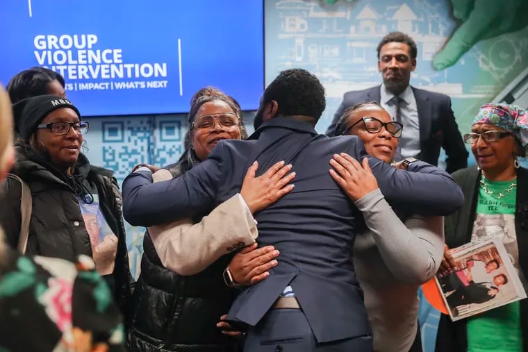 Deion Sumpter (center), the city's director of Group Violence Intervention, hugs the mothers he works with following a news conference about the initiative's effectiveness. The mothers in attendance lost children to gun violence, and work in the city’s GVI program to reduce group-member gun crime through social services and community-rooted messaging in Philadelphia’s most affected neighborhoods.
