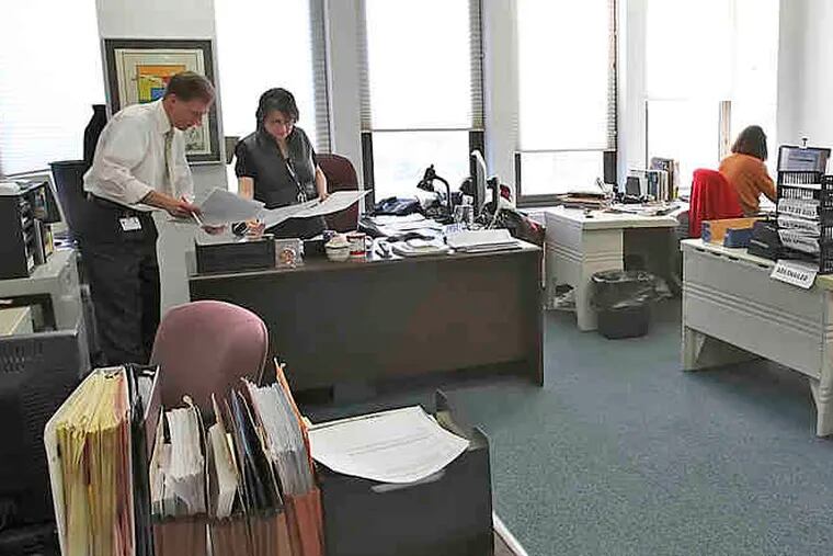 In the Catholic Standard and Times newsroom , managing editor Sarbina Vourvoulias consults with editor Matthew Gambino. The diocese is converting the weekly to a monthly and starting a magazine.