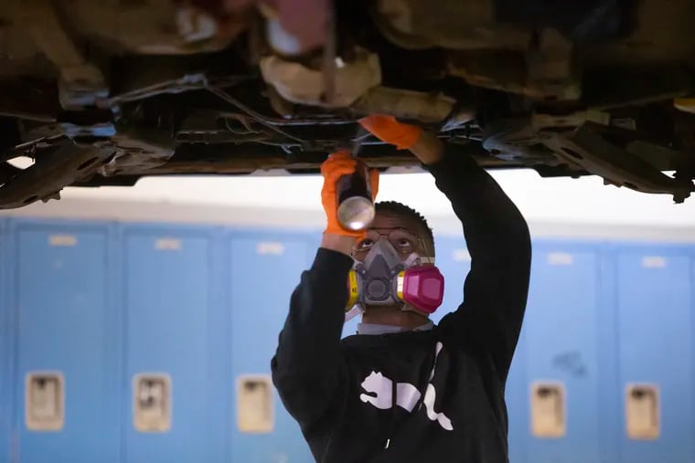 A student is shown working on a car at The Workshop School in West Philadelphia in this 2019 file photo. The school has been hit hard by changes to the Philadelphia School District's admissions policy.