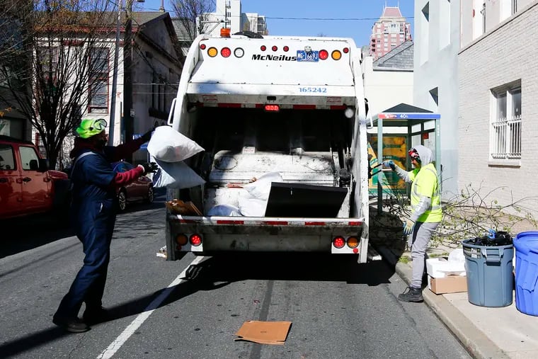 A City of Philadelphia sanitation worker tosses trash into a garbage truck along the 1100 block of Lombard Street.