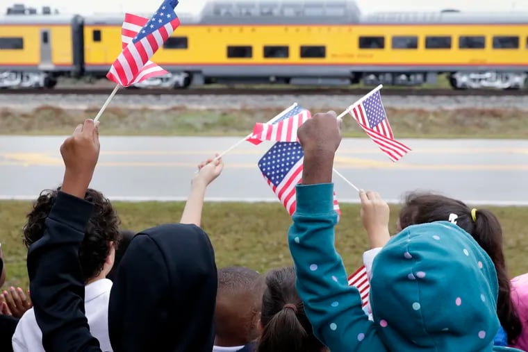 Students from Salyer Elementary School wave flags as the train carrying the body of former president George H.W. Bush travels past their school on the way to Bush's final internment Thursday, Dec. 6, 2018, in Spring, Texas. (AP Photo/Michael Wyke)