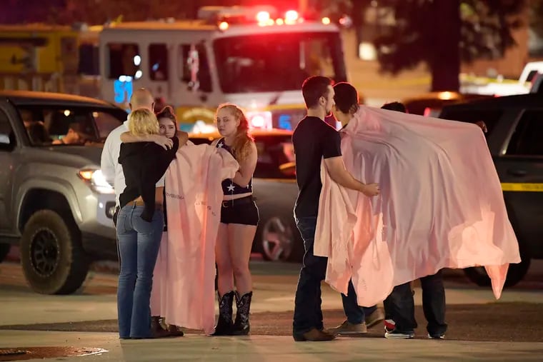 People comfort each other as they stand near the scene Thursday, Nov. 8, 2018, in Thousand Oaks, Calif. where a gunman opened fire Wednesday inside a country dance bar crowded with hundreds of people on "College Night."