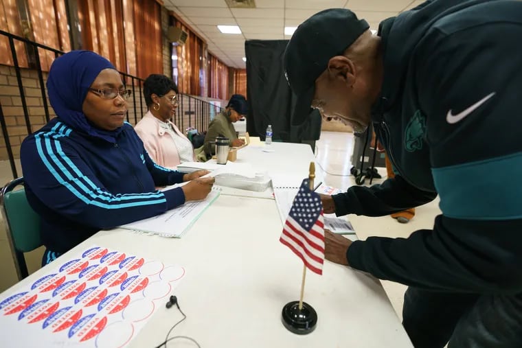 Ora Henry, left, signs in Otis Graham, right, as he votes on Election Day at Zion Baptist Church Of Philadelphia, located at Broad and Venango Streets, Nov. 5, 2019.