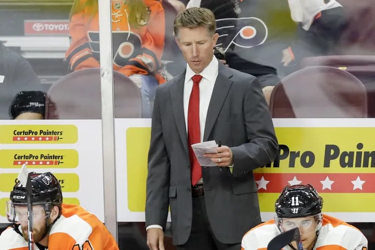 Flyers coach Dave Hakstol looks at his notes during a preseason game.