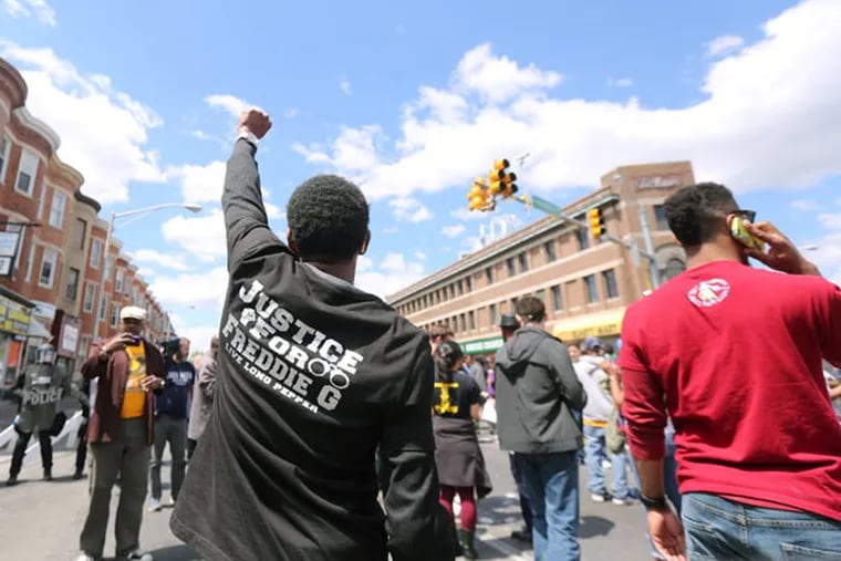 A protester raises a hand for Freddie Gray as Baltimore police block a section of West North Avenue at Pennsylvania Avenue on Tuesday, April 28, 2015. ( DAVID SWANSON / Staff Photographer )