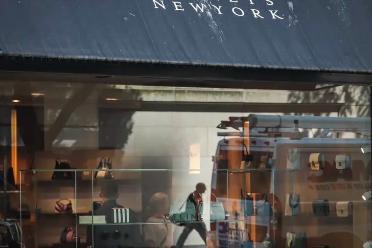 FILE - In this July 16, 2019, file photo a pedestrian reflect in a store window at Barneys department store in New York.  has filed for Chapter 11 bankruptcy protection, becoming the latest retailer unable to withstand the consumer shift to online shopping and high rents. Barneys said it’ll use the bankruptcy process to review store leases to best optimize its operations. The company also announced Tuesday, Aug. 6, that it has secured $75 million in new capital to facilitate a going concern sale process.