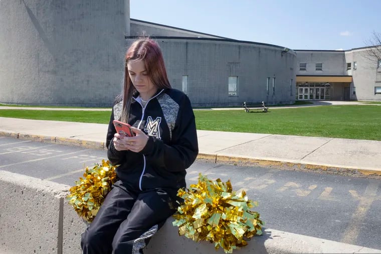 In this April 4, 2021, file photo provided by the American Civil Liberties Union, Brandi Levy wears her cheerleading outfit as she looks at her mobile phone outside Mahanoy Area High School in Mahanoy City, Pa.