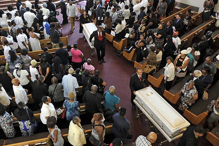 Two of three caskets leave the North Philadelphia Seventh-day Adventist Church for burial August 4, 2014, following funeral services for the three children killed last week in the North Philadelphia carjacking. ( TOM GRALISH / Staff Photographer )