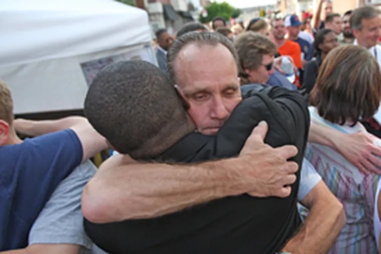 Floyd Liczbinski, facing the camera, hugs Try Baylor, a community activist, at a vigil yesterday for slain Philadelphia Police Sgt. Stephen Liczbinski. (Michael Bryant / Inquirer)