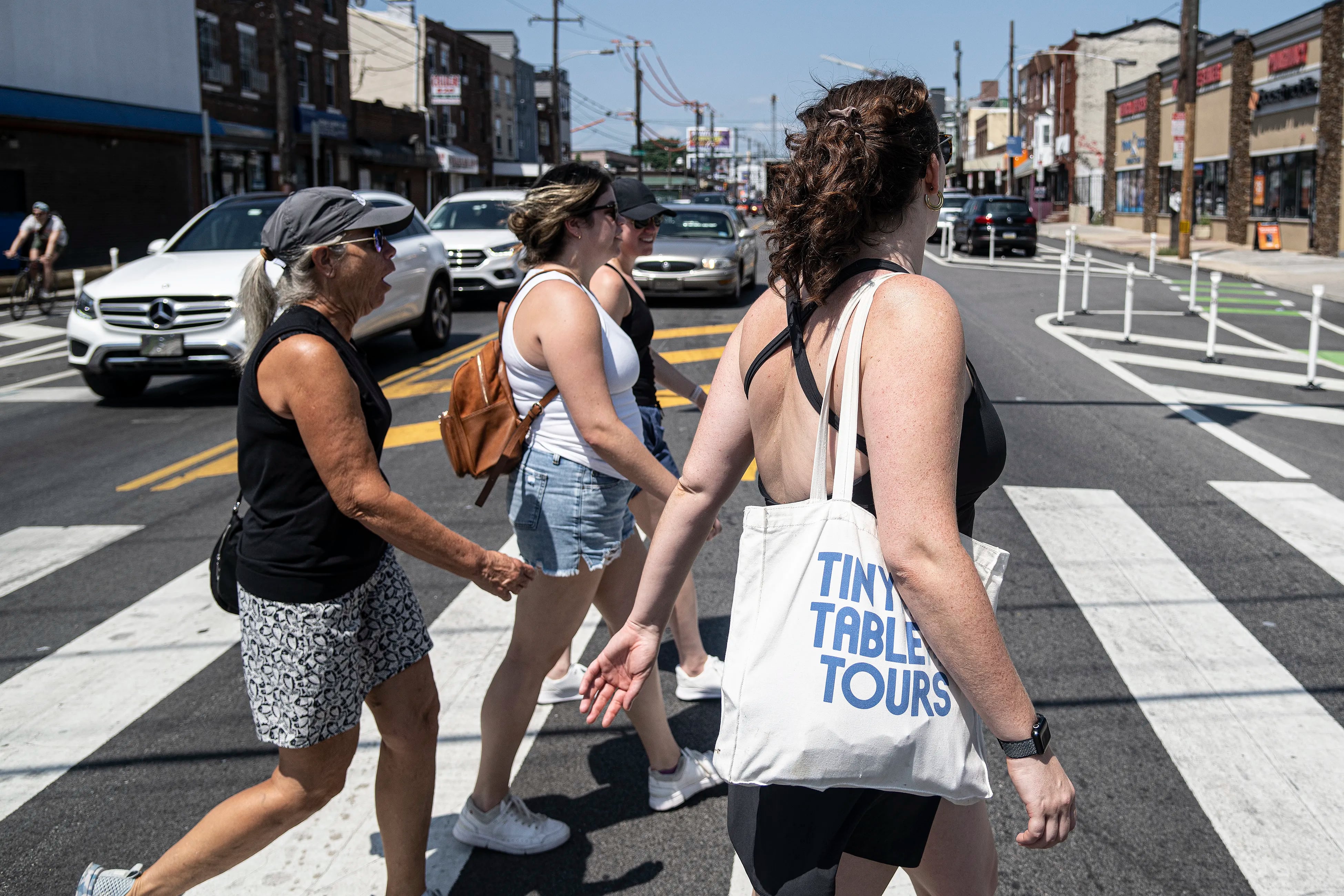 Maddy Sweitzer-Lammé (right), the founder of Tiny Table Tours, walks the streets of Philadelphia with Florida tourists Mary Pat Murphy (from left), Katie Murphy, and Maggie Murphy in South Philadelphia.