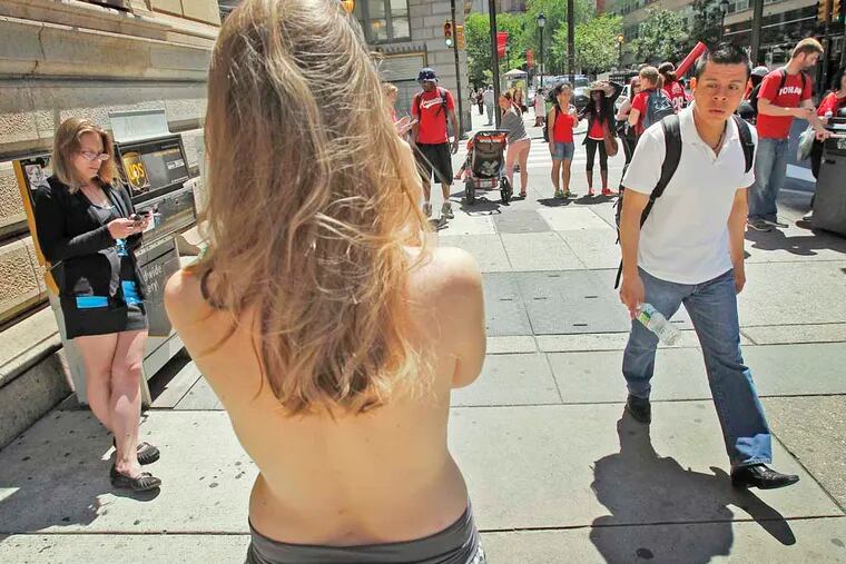 A seemingly confused man walks past Moira Johnston as she stands bared-breasted along Walnut Street near 18th on June 4, 2013. (ALEJANDRO A. ALVAREZ / STAFF PHOTOGRAPHER )