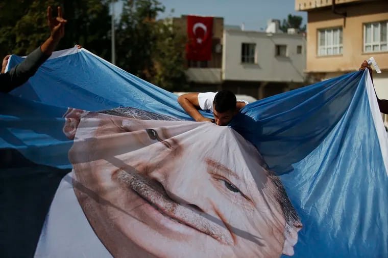A man kisses a poster of Turkey's President Recep Tayyip Erdogan during show of support by about a dozen people for Turkey's operation in Syria, in the border town of Akcakale, Sanliurfa province, southeastern Turkey, on Monday, Oct. 14, 2019. Erdogan has signaled that Turkish troops and their Syrian opposition allies are ready to launch an assault on the Syrian Kurdish held city of Manbij, Syria.